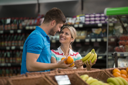 Beautiful Young Couple Shopping For Fruits And Vegetables In Produce Department Of A Grocery Store - Supermarket - Shallow Deep Of Fieldの写真素材