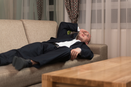 Handsome Young Man in Suit and Tie Sleeping or Resting in Sofaの写真素材