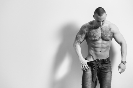 Portrait of a Sexy Naked Man In Jeans Showing His Abdominal Standing Isolated on Gray Backgroundの写真素材