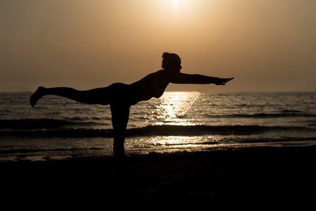 Young Healthy Woman Practicing Yoga Fitness Exercise on the Beach at Sunset - Healthy Lifestyle Concept - Copy Space Textの写真素材