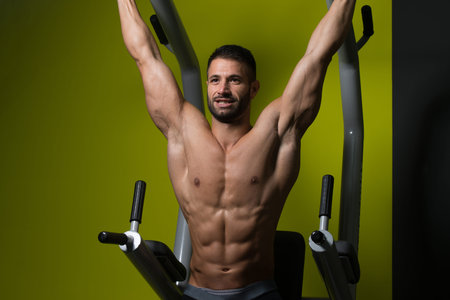 Muscular Man Performing Hanging Leg Raises Exercise - One Of The Most Effective Ab Exercises