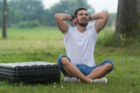 Portrait of Frustrated Young Engineer Sitting On Grass With Case from Droneの写真素材