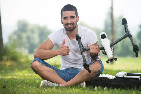 Portrait of Confident Young Engineer With Remote Control and Drone Gives Thumbs Up