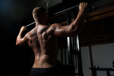 Muscular Athletic Bodybuilder Fitness Model Doing Heavy Weight Exercise For Back On Machine