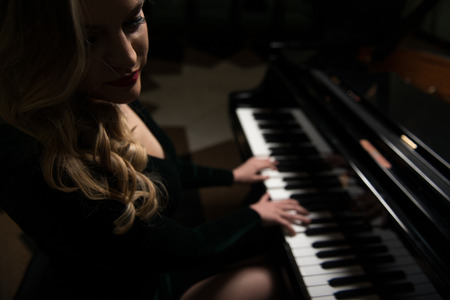 Beautiful Thoughtful Girl Sitting Near Piano - Fashion Studio Portraitの写真素材