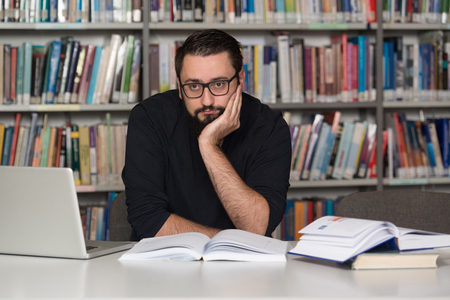 Sleeping Caucasian Student Sitting And Leaning On Pile Of Books In College - Shallow Depth Of Fieldの写真素材