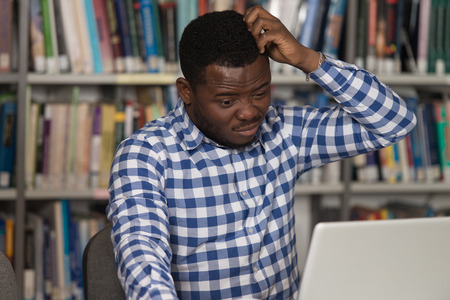 Stressed African Student Of High School Sitting At The Library Desk - Shallow Depth Of Fieldの写真素材