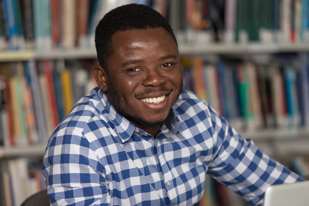 Portrait Of African Clever Student With Open Book Reading It In College Library - Shallow Depth Of Fieldの写真素材