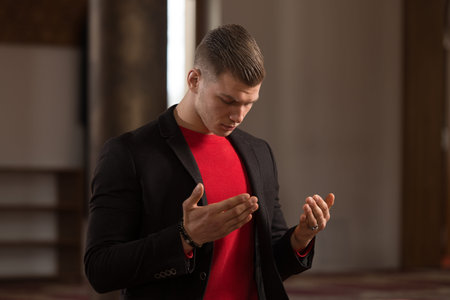Attractive Blond Man Making Traditional Prayer to God Allah in the Mosque