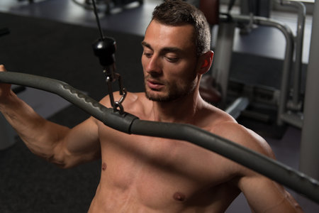 Handsome Bodybuilder Doing Heavy Weight Exercise For Back On Machine
