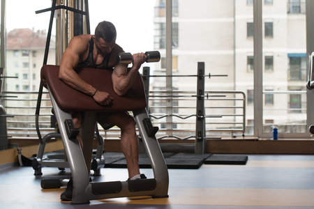 Man Working Out Biceps In A Gym - Dumbbell Concentration Curlsの写真素材