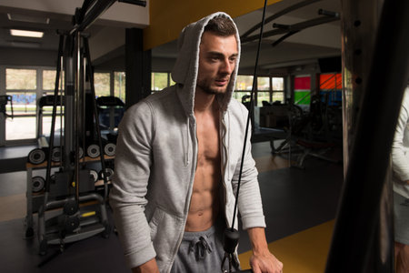 Muscular Fitness Bodybuilder Doing Heavy Weight Exercise For Triceps On Machine With Cable In The...