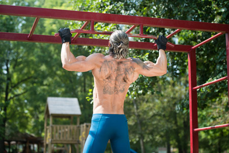 Muscular Built Athlete Working Out In An Outdoor Gym - Doing Chin-Ups