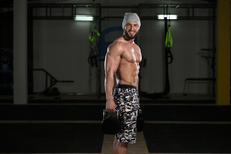 Young Man Exercising With Kettle Bell And Flexing Muscles - Muscular Athletic Bodybuilder Fitness Model Exercisesの写真素材