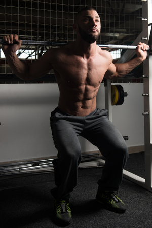 Healthy Fitness Man Working Out Legs With Barbell In A Gym - Squat Exerciseの写真素材