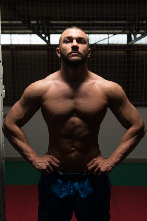 Healthy Young Man Standing Strong In The Gym And Flexing Muscles - Muscular Athletic Bodybuilder Fitness Model Posing After Exercisesの写真素材