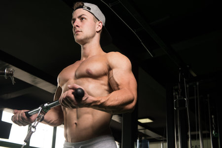 Handsome Muscular Fitness Bodybuilder Doing Heavy Weight Exercise For Biceps On Machine With Cable...