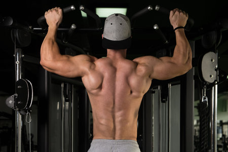 Young Man Athlete Doing Pull Ups - Chin-Ups In The Gym