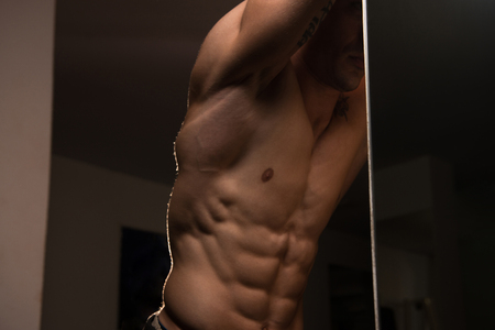 Portrait Of A Young Physically Fit Man Showing His Well Trained Abdominal Muscle - Muscular Athletic Bodybuilder Fitness Model Posing After Exercisesの写真素材