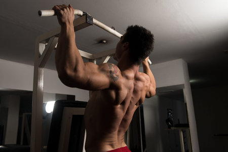 Young Man Athlete Doing Pull Ups - Chin-Ups In The Gym