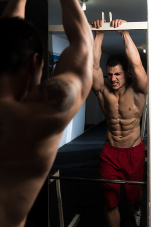 Handsome Man Standing Strong In The Gym And Flexing Abdominal Muscles - Muscular Athletic Bodybuilder Fitness Model Posing After Exercisesの写真素材