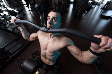 Handsome Athlete Doing Heavy Weight Exercise For Back On Machine