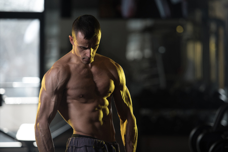 Muscular Man Exercising Abdominal Muscles With Weights In A Modern Fitness Clubの写真素材