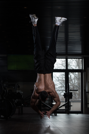 Young Man Athlete Doing Extreme Pushups Handstand As Part Of Bodybuilding Trainingの写真素材