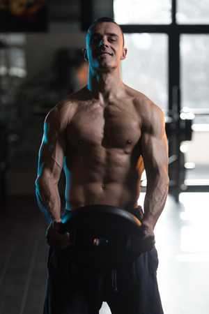 Muscular Man Exercising Abdominal Muscles With Weights In A Modern Fitness Clubの写真素材