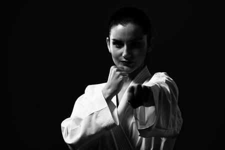 Young Woman Practicing Her Karate Moves - White Kimono - Black Beltの写真素材