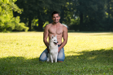 Sexy Young Man Holding Dog German Spitz In Park - Together Enjoying The Viewの写真素材
