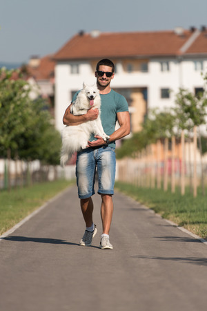 Young Man And German Spitz Walk In The Park - He Keeps The Dog On The Leashの写真素材