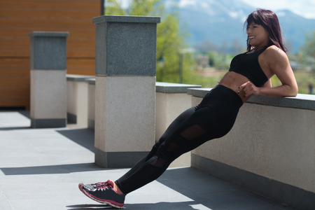 Attractive Woman Resting On Concrete Outdoors After Exercise In Fitness Centerの写真素材