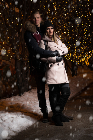 Having Fun Together at a Christmas Fairy. Young Cheerful Couple Is Having a Walk. Enjoying, Dressed Warm, Looking at Each Other and Laughの写真素材