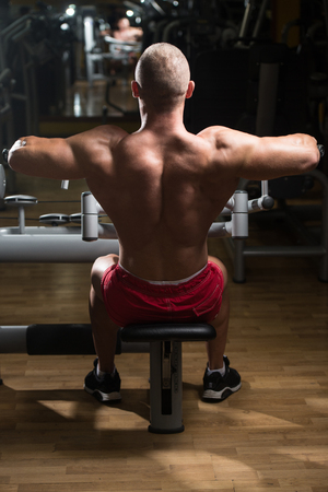 Handsome Athlete Doing Heavy Weight Exercise For Back On Machineの写真素材