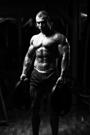 Portrait Of A Physically Young Man Holding Weights In Handの写真素材
