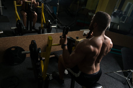 Handsome Bodybuilder Doing Heavy Weight Exercise For Back On Machine