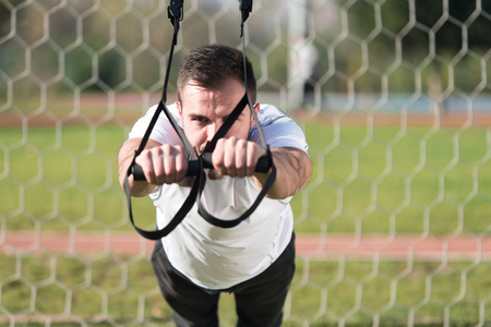 Attractive Man Doing Crossfit With Trx Fitness Straps in City Park Area - Training and Exercising for Endurance - Healthy Lifestyle Concept Outdoorの写真素材