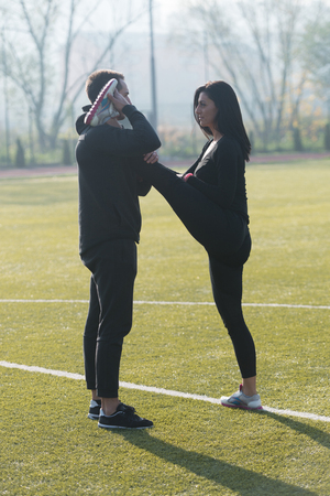 Young Couple Stretching Before Running In City Park Area - Training And Exercising For Trail Run Marathon Endurance - Fitness Healthy Lifestyle Concept Outdoorの写真素材