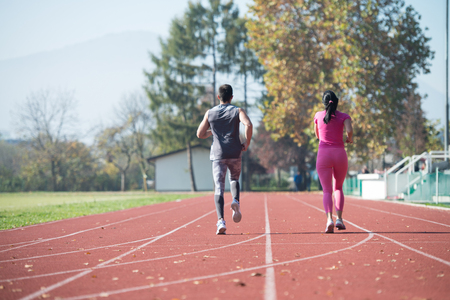Attractive Couple Sprinting on the Running Track in City Park Area - Training and Exercising for Endurance - Fitness Healthy Lifestyle Concept Outdoorの写真素材