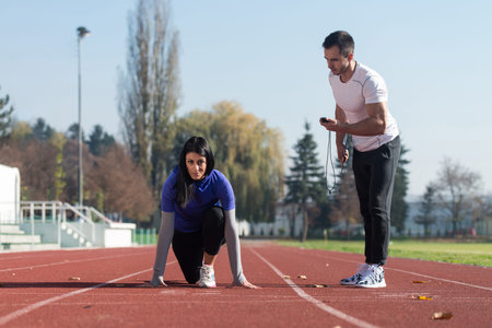 Athletic Personal Trainer Helping Female To Sprint on the Running Track in City Park Area - Training...