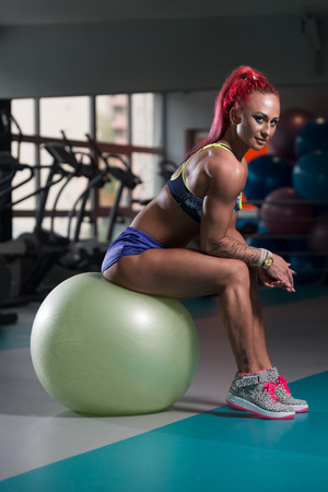 Attractive Woman Resting On Ball After Exercise In Fitness Centerの写真素材