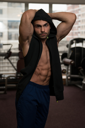 Young Muscular Man In Black Hooded Sweatshirt Showing Musclesの写真素材