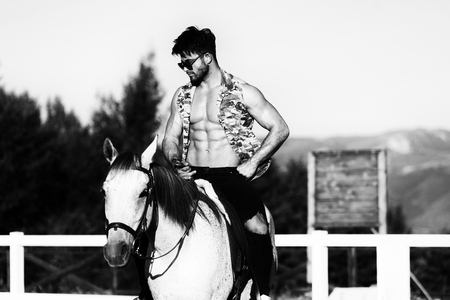 Handsome Macho Man Cowboy Riding on a Horse - Background of Sky and Mountainsの写真素材