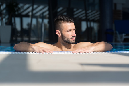 Happy Attractive Man Resting Relaxed On Edge Of Swimming Poolの写真素材