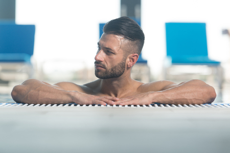 Happy Attractive Man Resting Relaxed On Edge Of Swimming Poolの写真素材