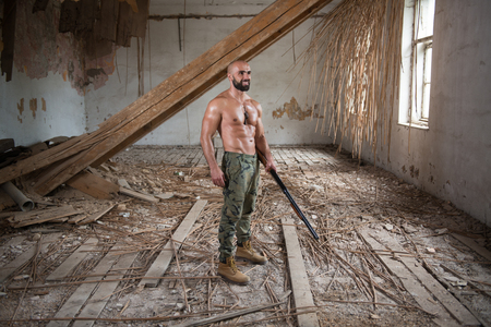 Action Hero Muscled Man Holding Machine Gun - Standing In Abandoned Building Wearing Army Pantsの写真素材