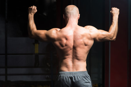 Healthy Young Man Standing Strong In The Gym And Flexing Muscles - Muscular Athletic Bodybuilder...