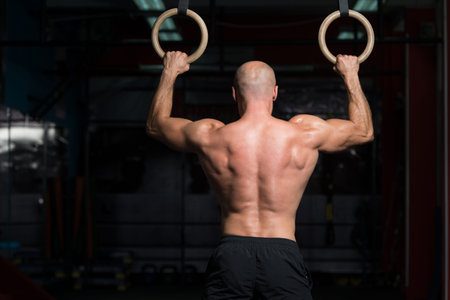 Adult Man Exercising While Holding Large Gymnastic Rings At The Gym