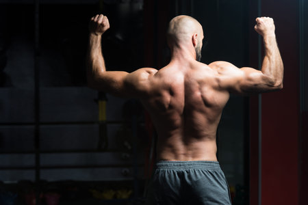 Handsome Young Man Standing Strong In The Gym And Flexing Muscles - Muscular Athletic Bodybuilder...